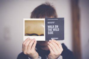 A man holds up a card that reads take a walk on the wild side with impossible underneath. Could this be your call to action for a freelance side hustle or collaboration?