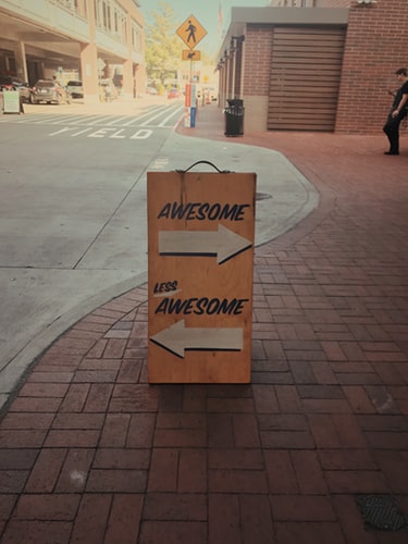 A sign stands in the street pointing arrows left and right to awesome and less awesome. It's used to demonstrate a discussion on th art of feedback.