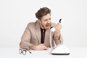 Illustrating the anger of a troublesome freelance client by having a man in a suit yell into an old fashioned dial up telephone