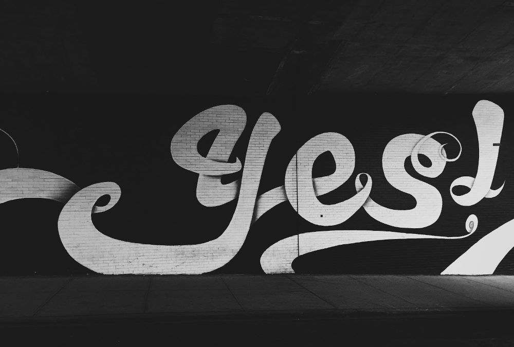 A black wall with the word yes painted on it in flourshing letters