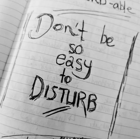 A sketch book is open with "don't be so easy to disturb" written in it to demonstrate the slow business movement. A movement that focuses on single focus and slowing down while doing business and work.