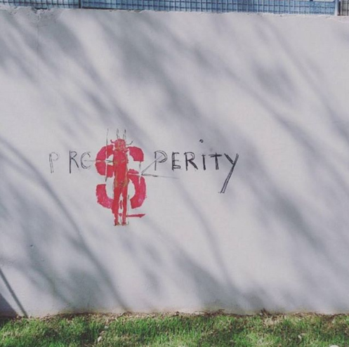 Instagram filtered photograph of graffiti at Parramatta river in NSW Australia tat reads prosperity with a dollar sign where the S should be. This is the constant battle of freelancers to define freelance success as money or lifestyle.