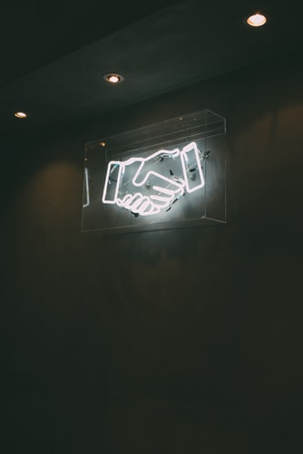 Neon sign of a handshake to signify managing clients