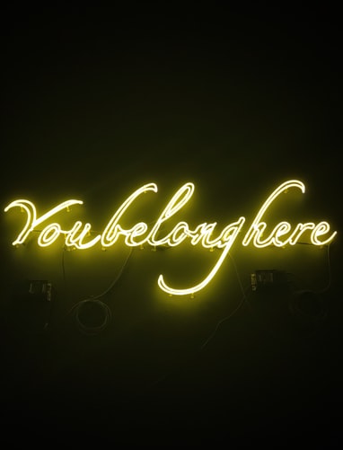 Neon sign that reads you belong here in cursive to signify online networking and connectivity