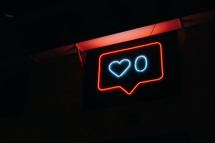 to demonstrate freelance social media, a neon sign with a love heart and a zero hangs inside a conversational bubble