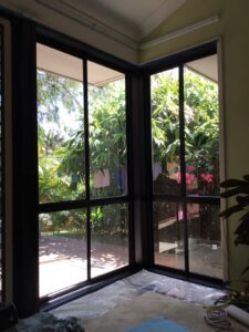 A black framed outdoor area shows off a lush green garden through sliding doors