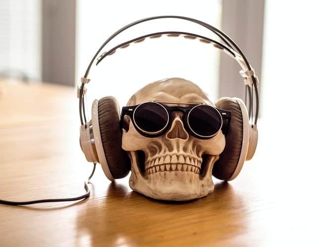 A skull is on a desk wearing headphones to demonstrate sound freelance self-care practises in the office.