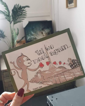 A n illustrated postcard that features a Freelance Jungle minkey sends a love heart to the city of Melbourne. It was sent during October to recognise the impact of freelancing under covid. It is held by a thumb with red nail polish in a lounge room with a plant.