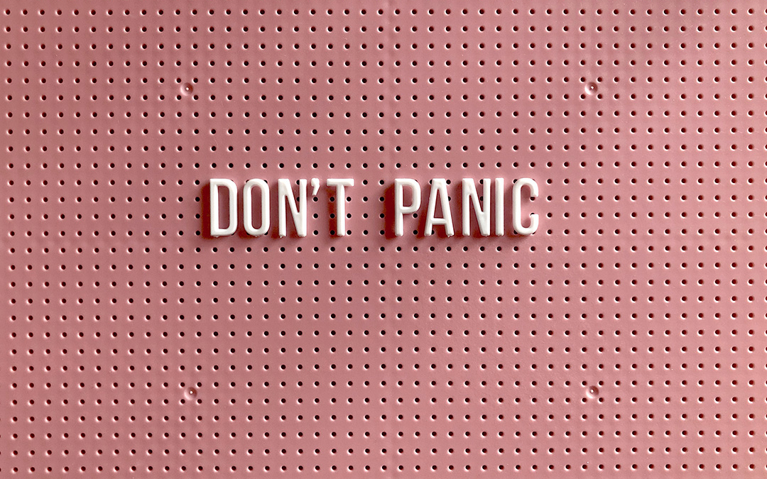 The words "don't panic" are spelt out in plastic letters on a pink noticeboard.