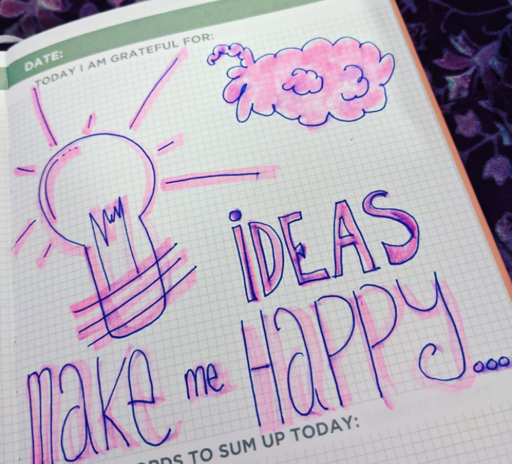 A light bulb next to a brain in a journal stating 'ideas make me happy' in relation to freelance content marketing.
