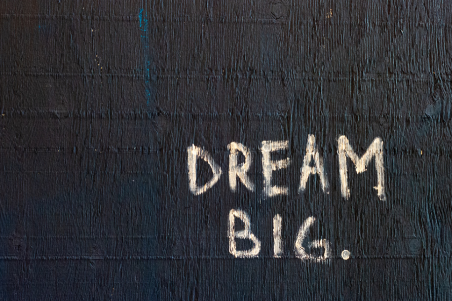 Dream big is written on a dark wall in chalk to indicate dreaming about freelance product ideas.