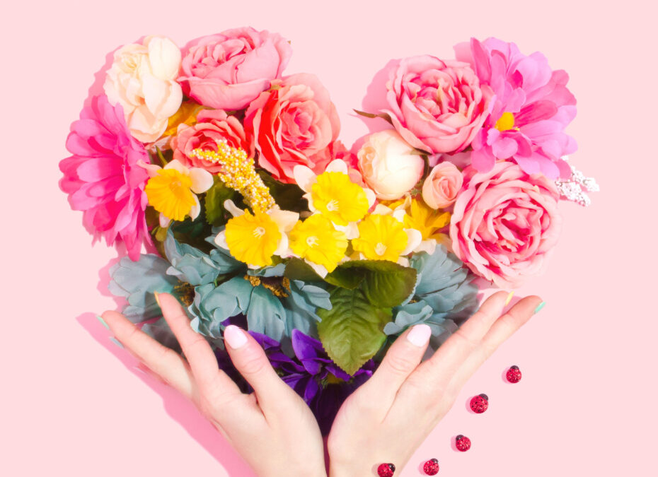 a heart-shaped bouquet of flowers in two hands