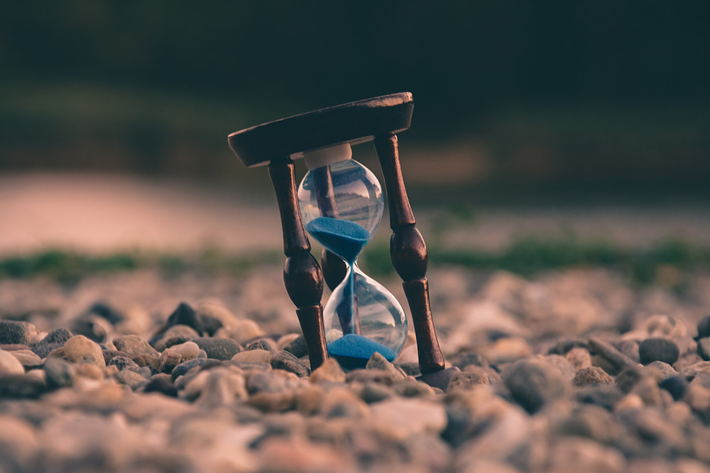 an hourglass sits sideways on rocks like time and creativity as they meet in freelancing