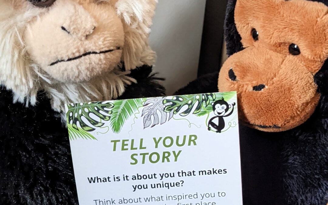 two toy minkeys are around a card that says 'tell your story'